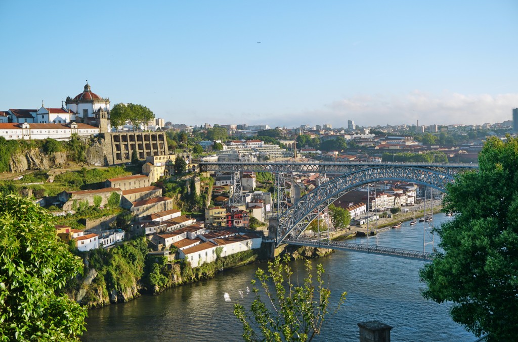 Vibrant cityscape with a bridge spanning a river and historic buildings on a hillside