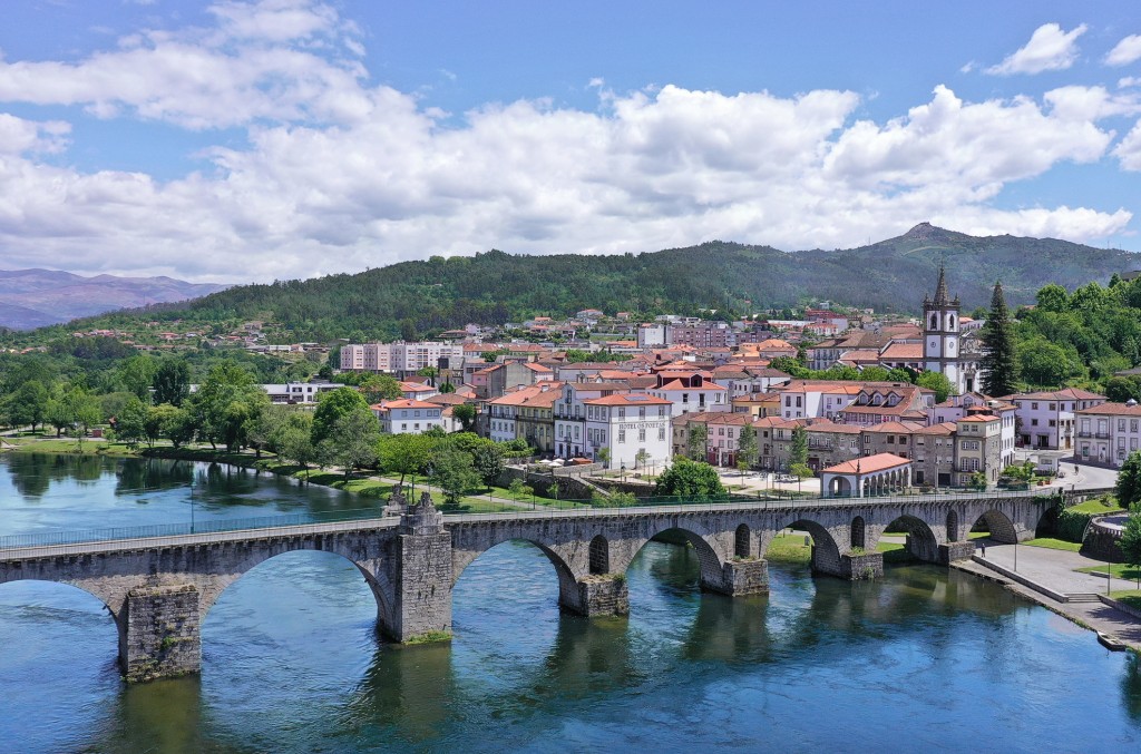 Historische Stadt mit Brücke über blauem Fluss unter bewölktem Himmel