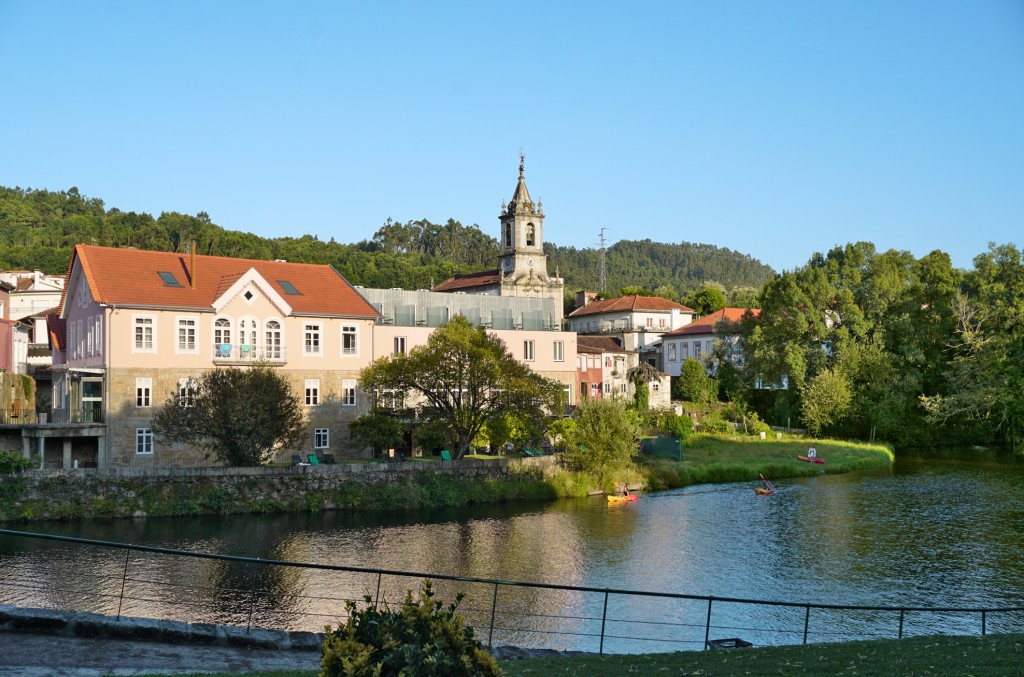 Ein Dorf mit Kirche und Häusern liegt am Ufer eines ruhigen Sees.
