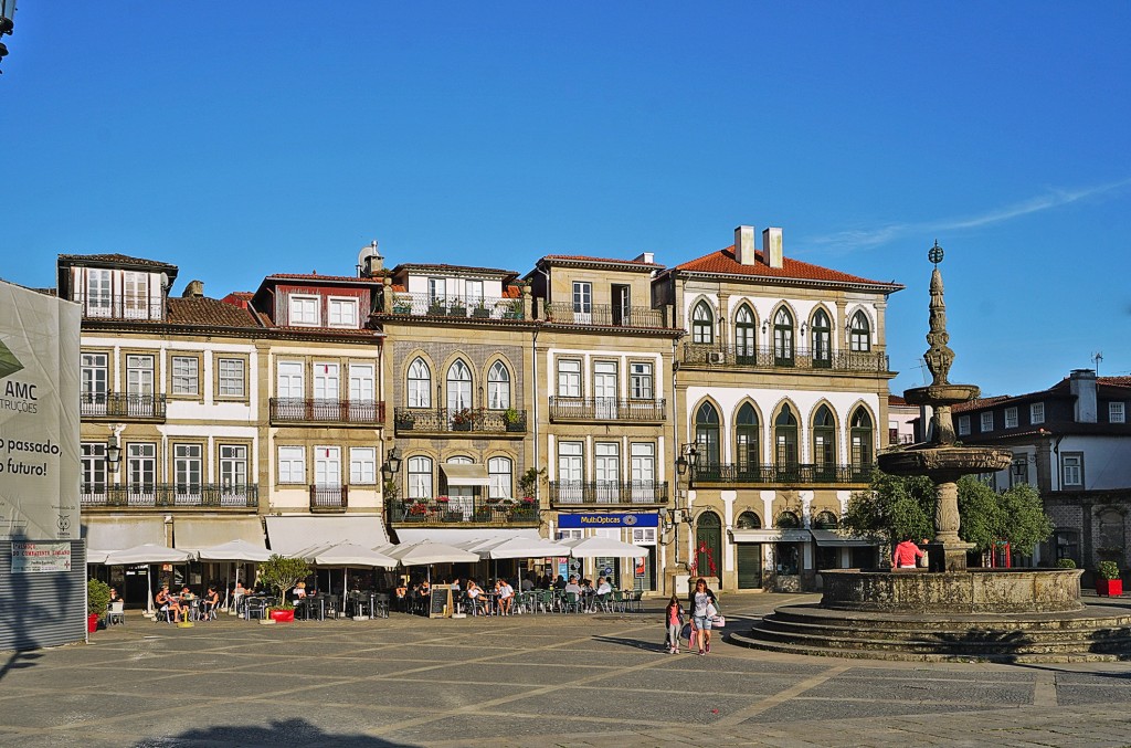 Historisches Gebäude mit Fassade und Brunnen auf einem belebten Platz in Portugal