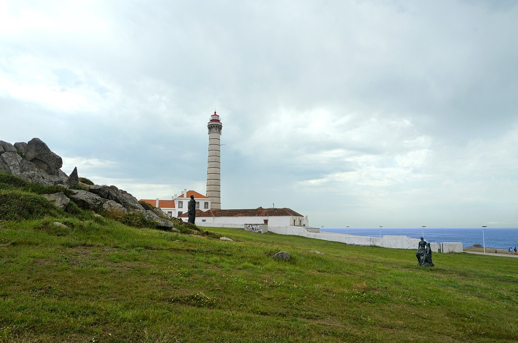 White lighthouse stands tall on a grassy clifftop overlooking the ocean