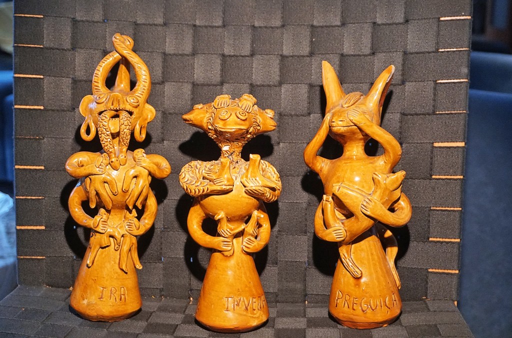 Drei Terrakottafiguren mit verschiedenen Gesichtsausdrücken und Beschriftungen stehen nebeneinander