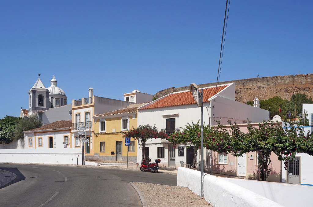 Colorful houses line a street with a church visible in the background