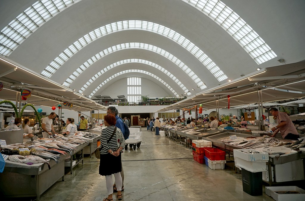 Ein lebhafter Fischmarkt mit vielen Ständen und Besuchern unter einer hohen gewölbten Halle