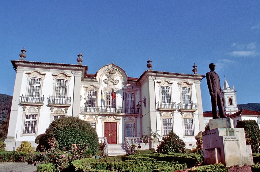 Prunkvolles Gebäude mit Statue davor und blauem Himmel im Hintergrund.