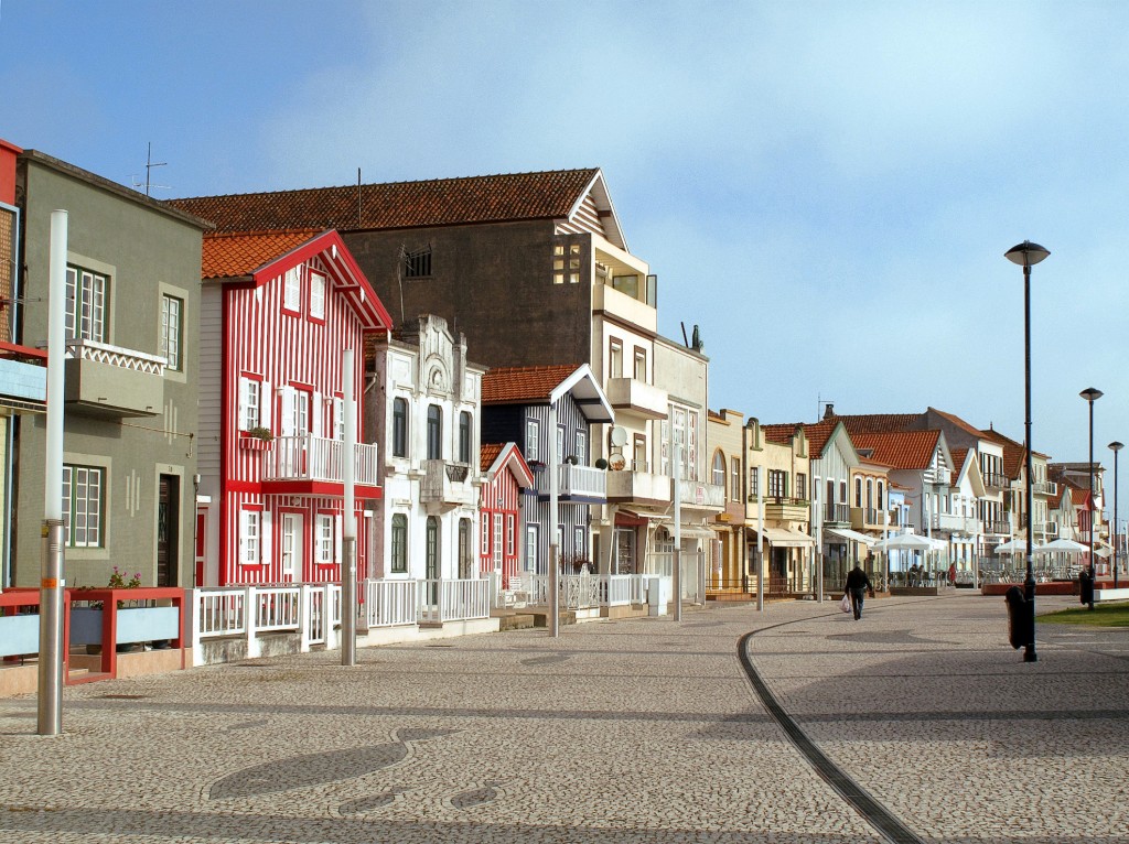 Bunte Häuserreihen säumen eine gepflasterte Straße in einer sonnigen Küstenstadt