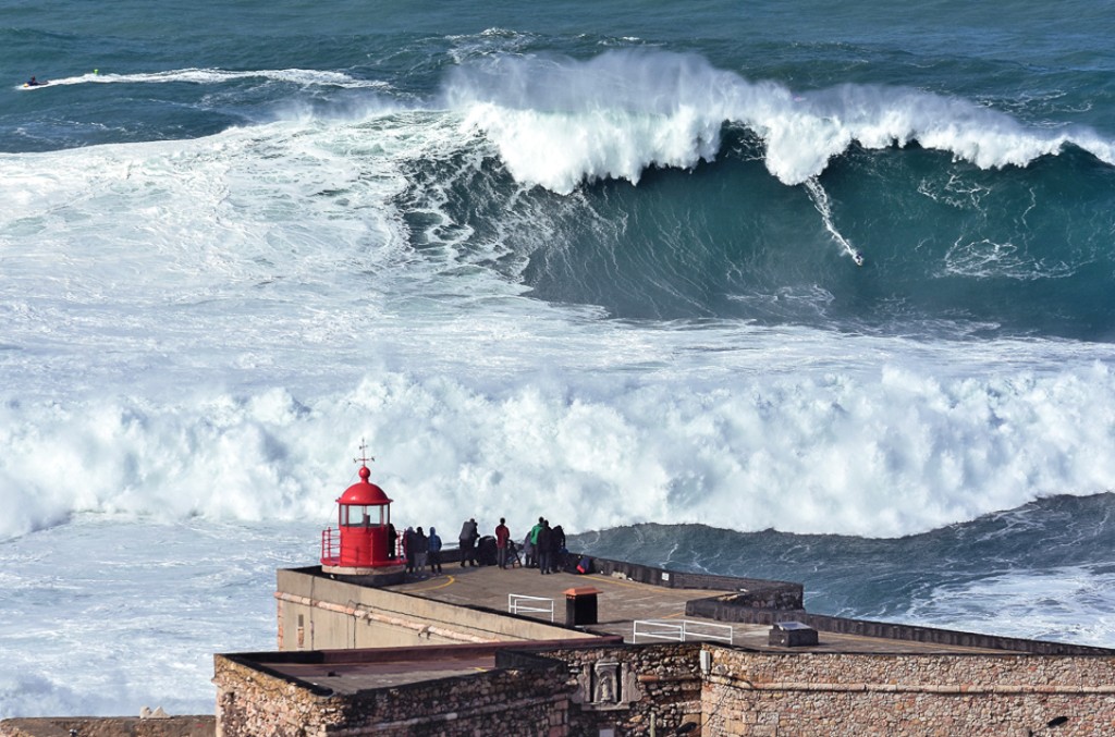 Majestätische Welle tobt neben einem Leuchtturm an der Küste