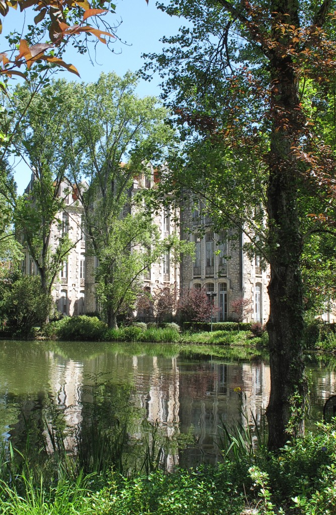 Ein Gebäude spiegelt sich in einem See wider umgeben von grüner Vegetation.