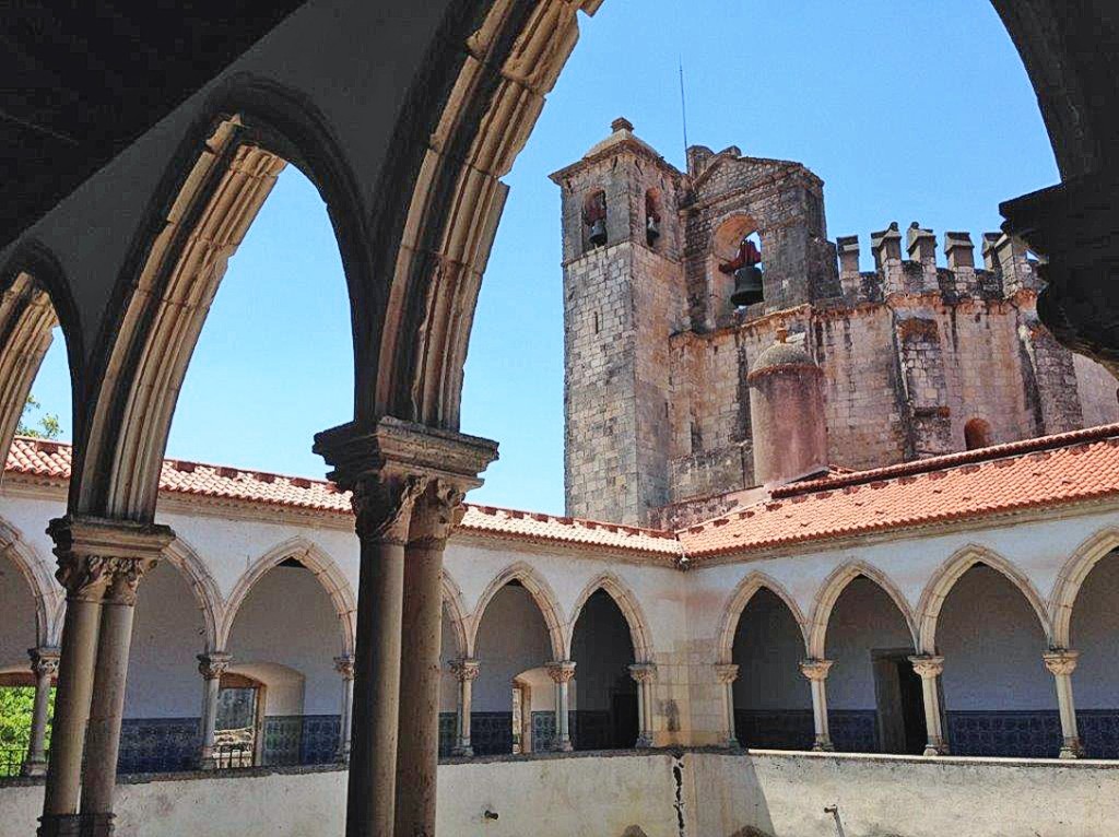 Ein Kloster mit Säulengängen und einem hohen Turm im Hintergrund
