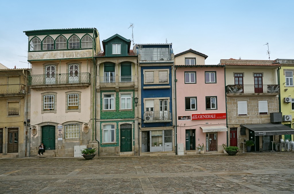 Colorful buildings line a square with ornate balconies and shop fronts