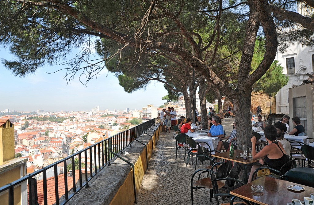 Terrasse mit Blick auf eine Stadt und Menschen bei einem Essen.