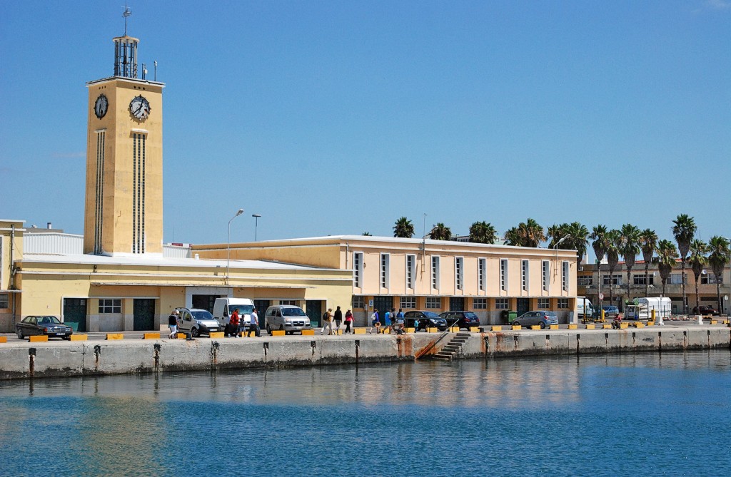 Ein Gebäude mit einem Glockenturm steht am Hafen mit Blick auf blaues Wasser