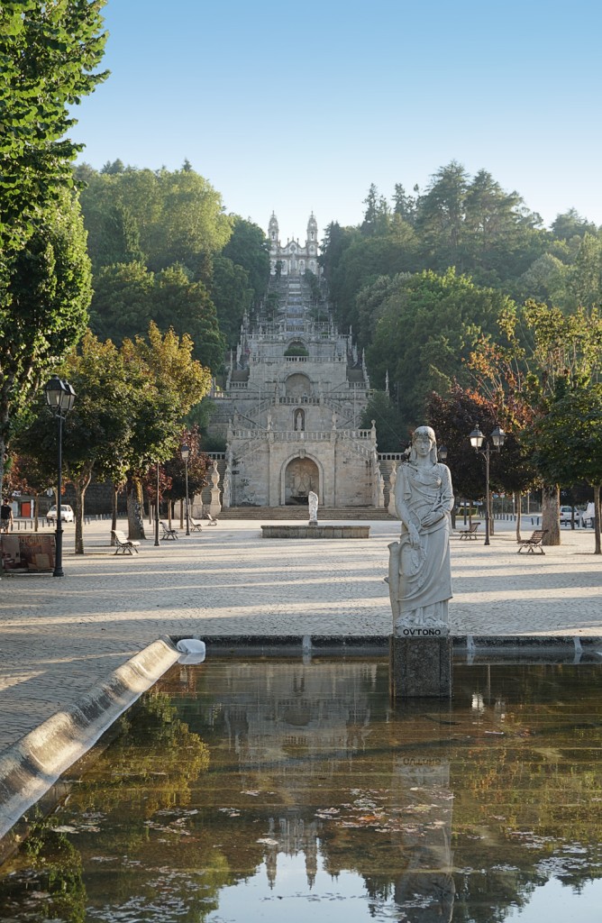Statue overlooks a grand staircase leading up a ornate hillside palace