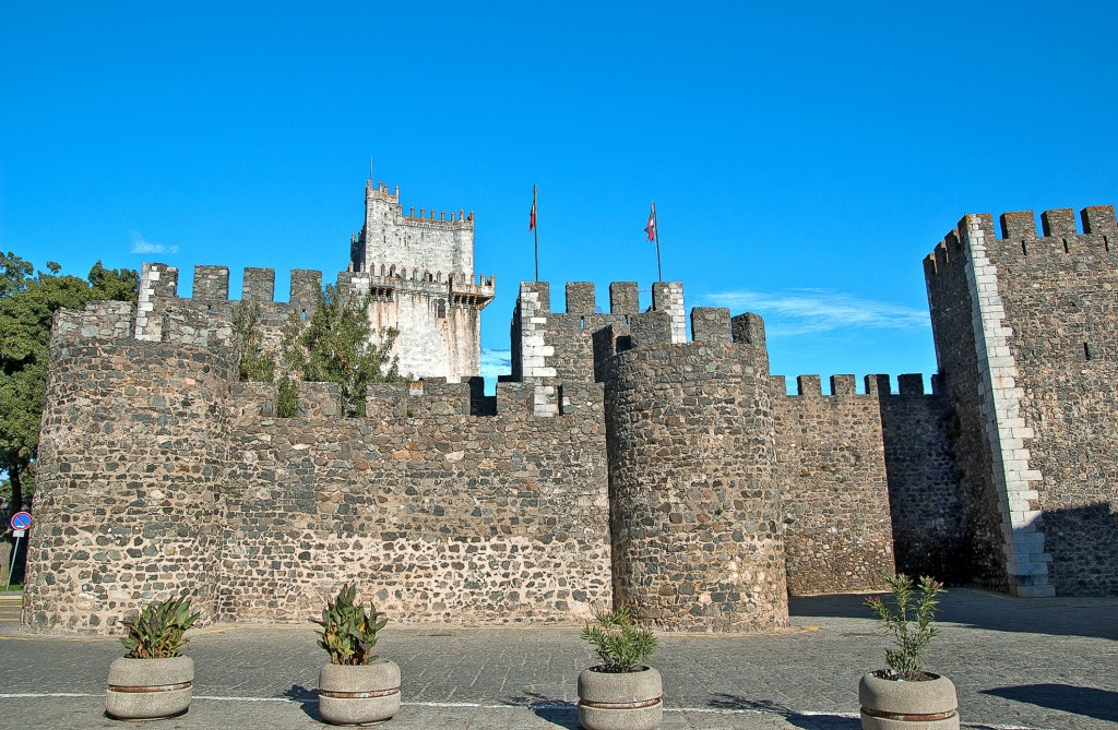Eine Burg mit Zinnen und Steinmauer unter blauem Himmel.