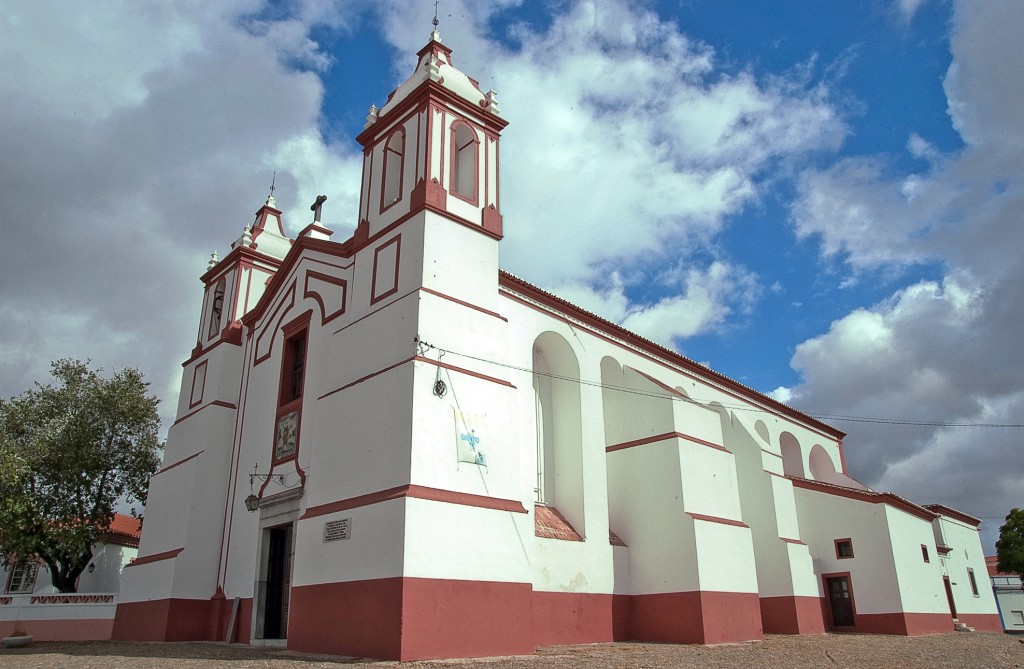Weiße Kirche mit roten Akzenten unter blauem Himmel