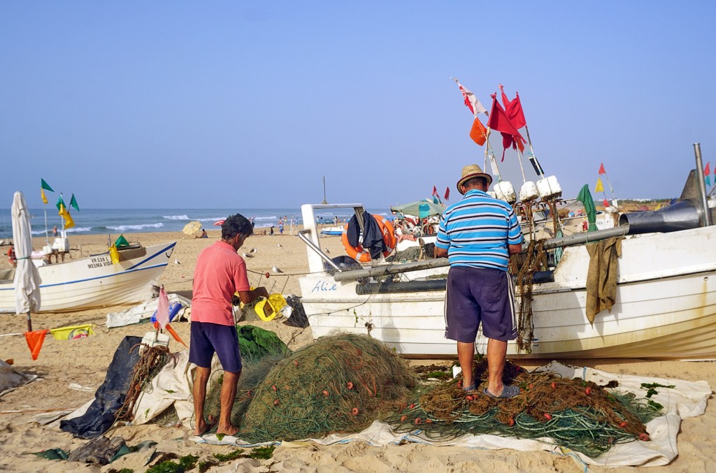 Fischer arbeiten an ihren Booten am Strand bei hellem Sonnenschein