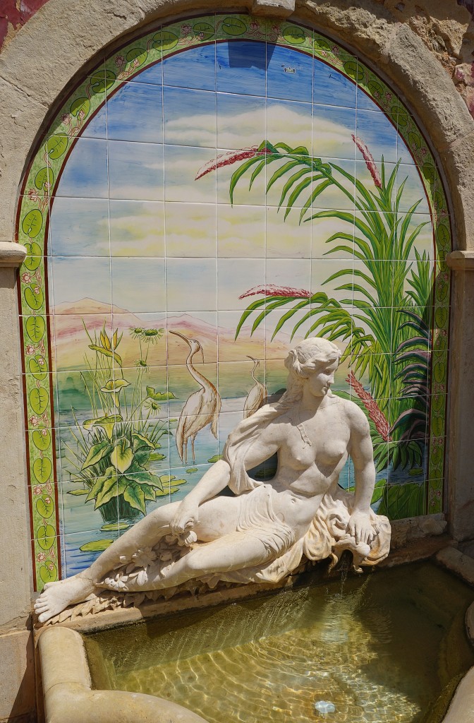 Eine Marmorstatue einer Frau auf einem Becken mit einem Mosaikhintergrund