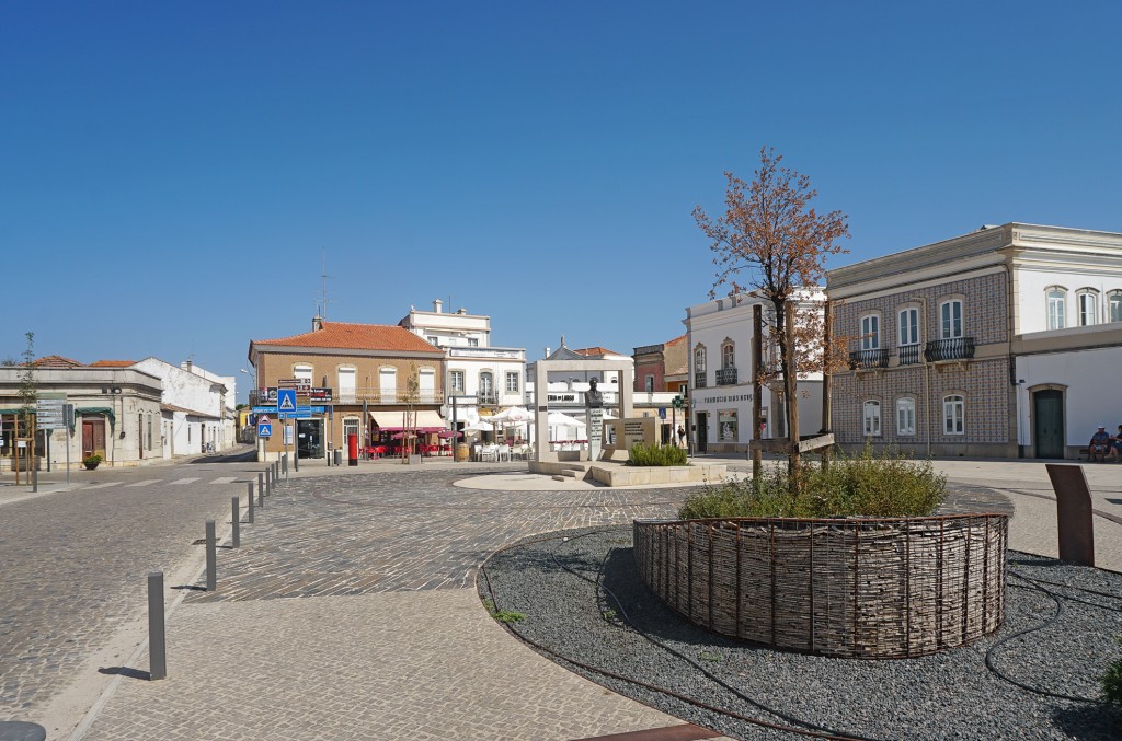 Historischer Stadtplatz mit Fassaden und einer kleinen Pflanzung im Vordergrund