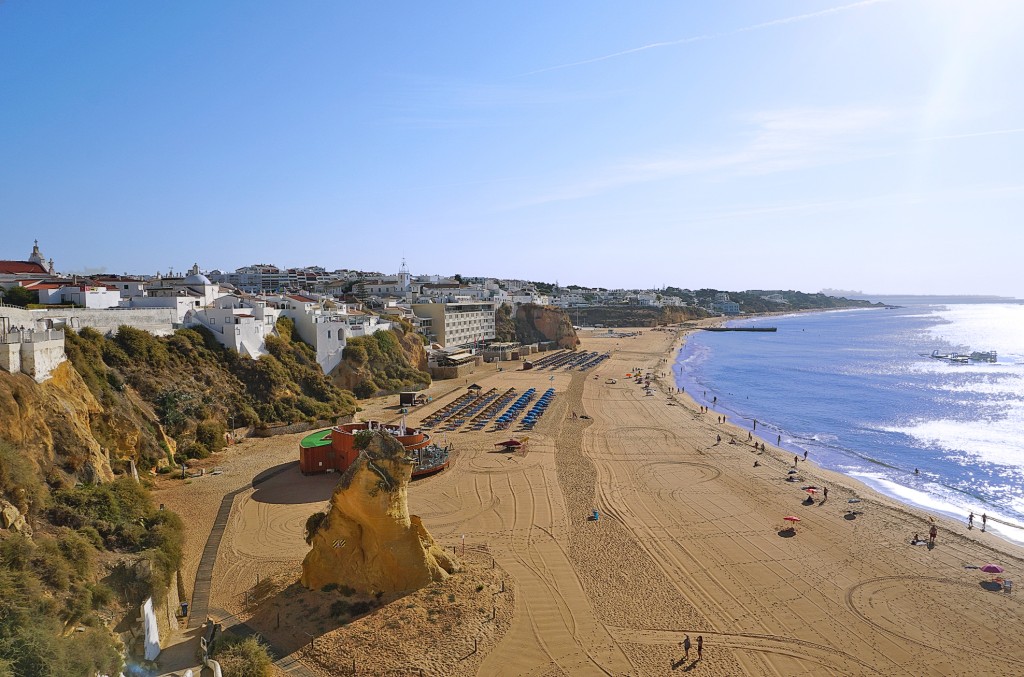Weitläufiger Sandstrand mit Klippen und blauem Meer im Hintergrund