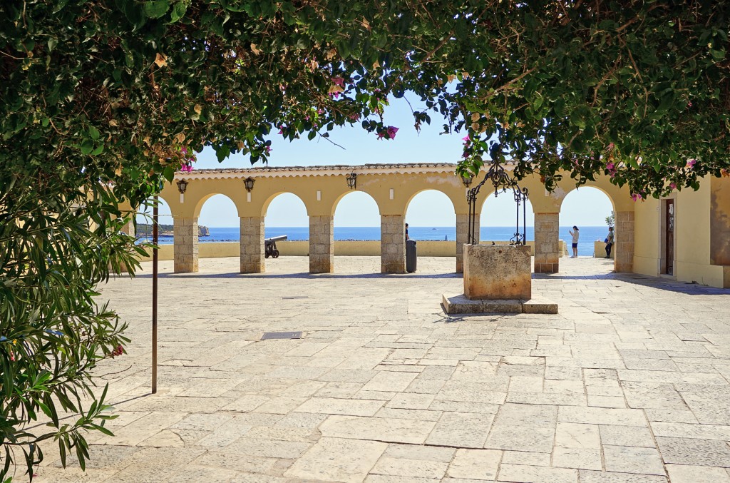 Eine Terrasse mit Bogen und Blick auf das Meer mit Kanonen im Vordergrund.