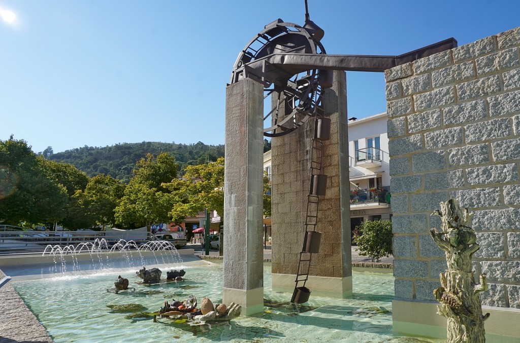 Brunnen mit Wasserrad und Skulpturen in einem öffentlichen Park